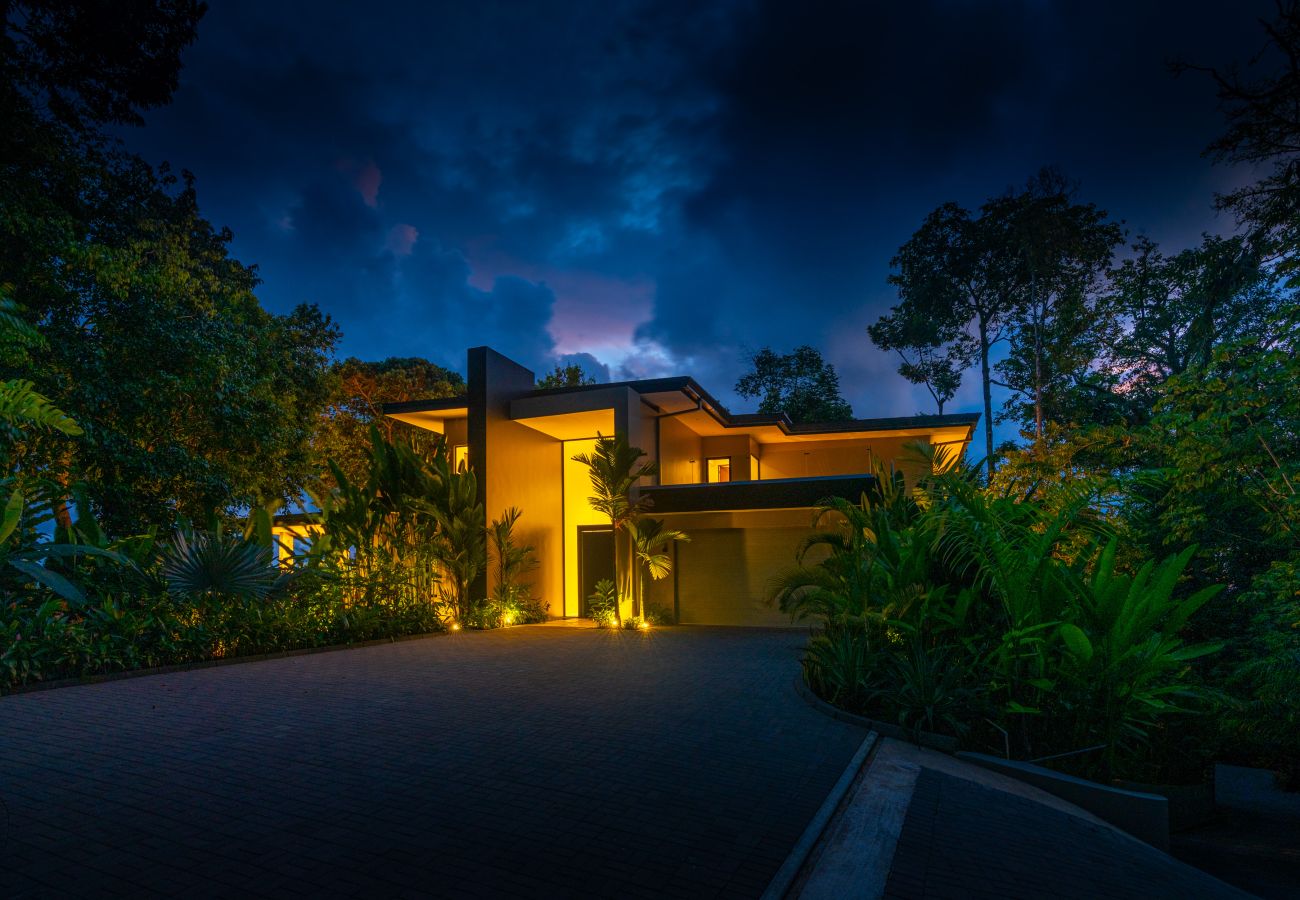 Villa exterior illuminated at night surrounded by tropical forest
