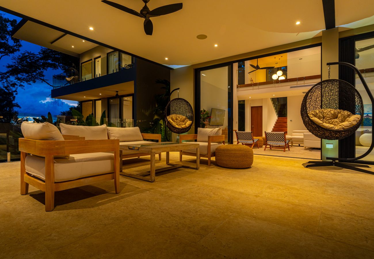 Outdoor living space lit at night with seating and jungle views