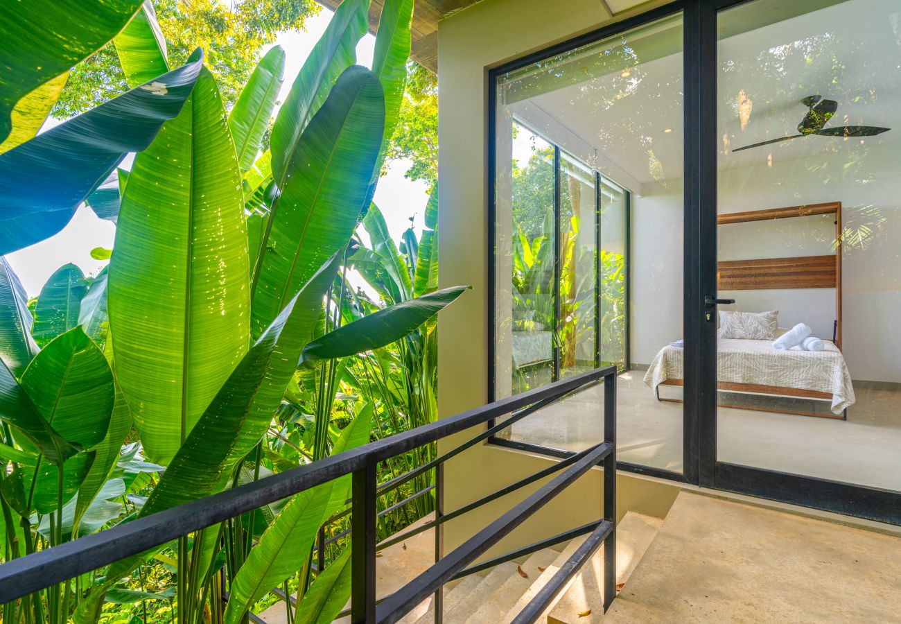 Bedroom with large windows overlooking tropical plants