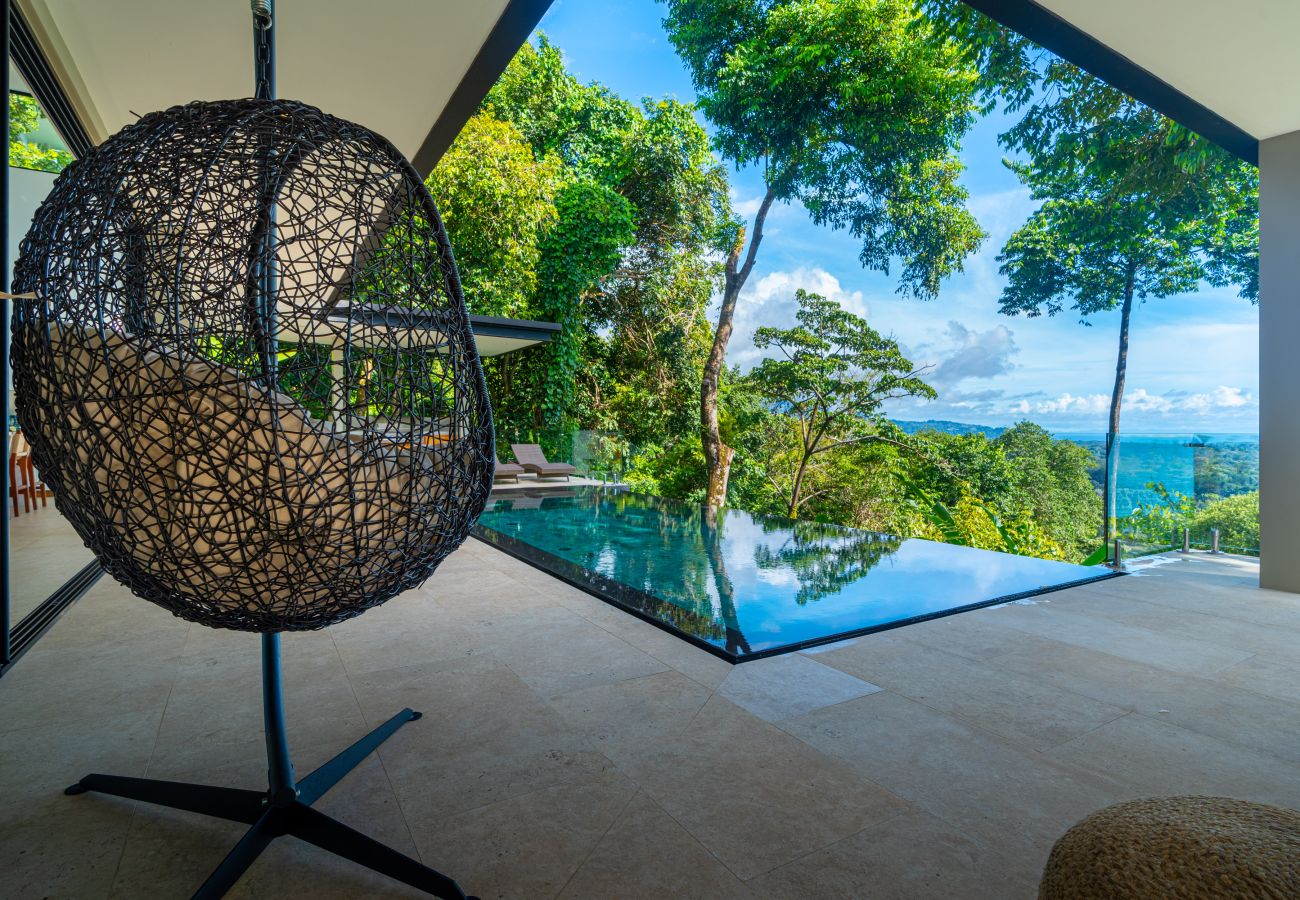 Hanging chair positioned near glass railing with ocean view