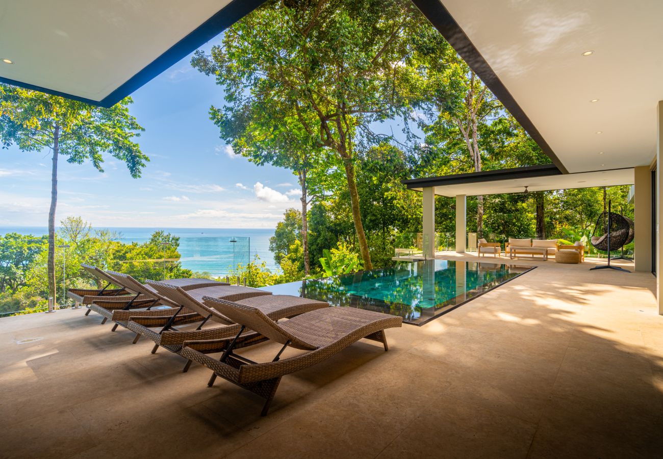 Lounge chairs on a covered terrace surrounded by jungle
